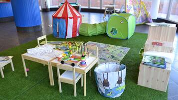 Een speelruimte met een tafel, stoelen, een tent en een speelhuis.