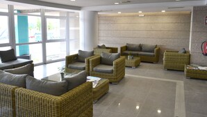 Un vestíbulo moderno con mobiliario de mimbre, ventanas amplias y una pared de piedra.