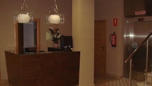 Un mostrador de recepción con suelo de mármol, un extintor y una escalera.