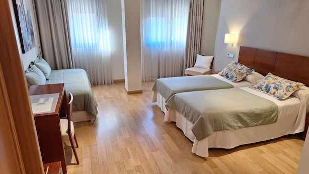 Habitación de hotel con dos camas, un escritorio y una silla.