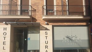 Entrada de un hotel con un letrero que dice "ASTURA HOTEL" y una puerta de acceso visible.