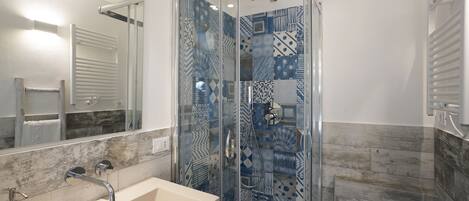 A modern bathroom with a glass-enclosed shower, a large mirror, and a beige sink.