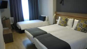 A hotel room with two beds, a flat-screen TV, a desk, and a window with curtains.