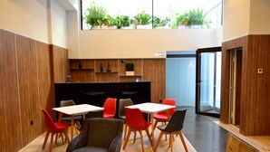 Un interior moderno con paneles de madera, una zona de estar central con sillas rojas y negras, y un televisor de pantalla plana grande.