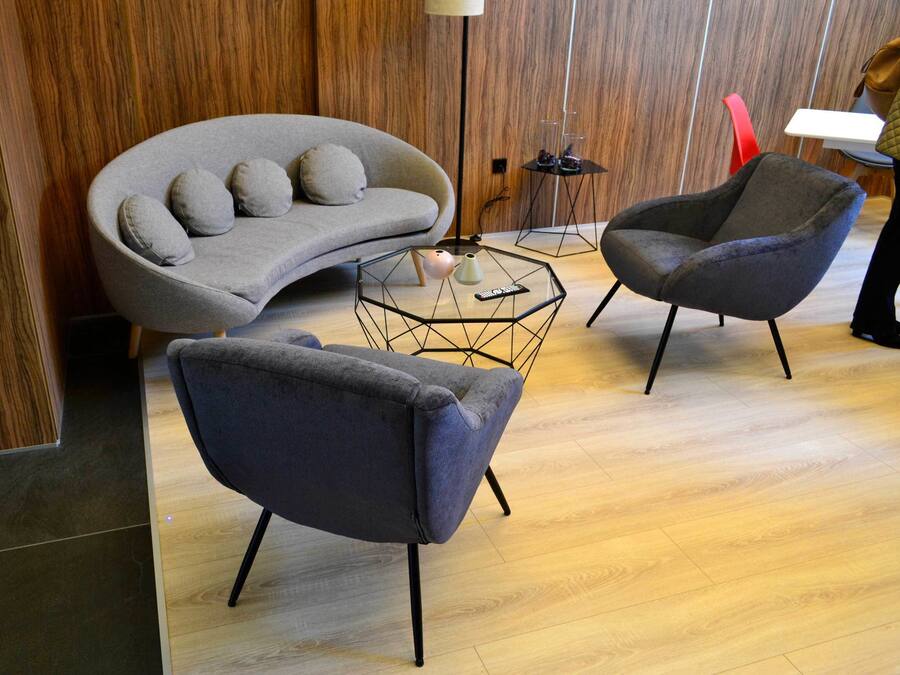 A modern living room with a grey sofa, two armchairs, and a geometric coffee table.