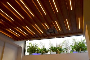 A ceiling with linear lighting fixtures and a clock. - Alda Estación Ourense (Ourense)