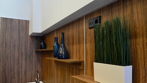 Una cocina moderna con armarios de madera, un lavamanos de acero inoxidable y jarrones azules decorativos en una estantería.