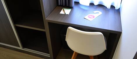 A small, dark wood desk with a white chair, a notepad, and a pink card with a heart symbol.