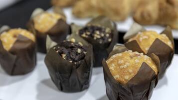 A tray of pastries in paper cups, including chocolate and sugar-dusted ones.