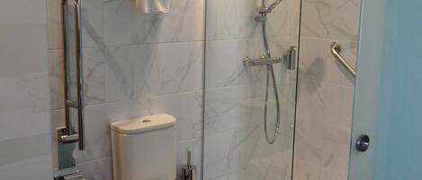 A modern bathroom with a toilet, a glass-enclosed shower, and a towel rack with folded towels.