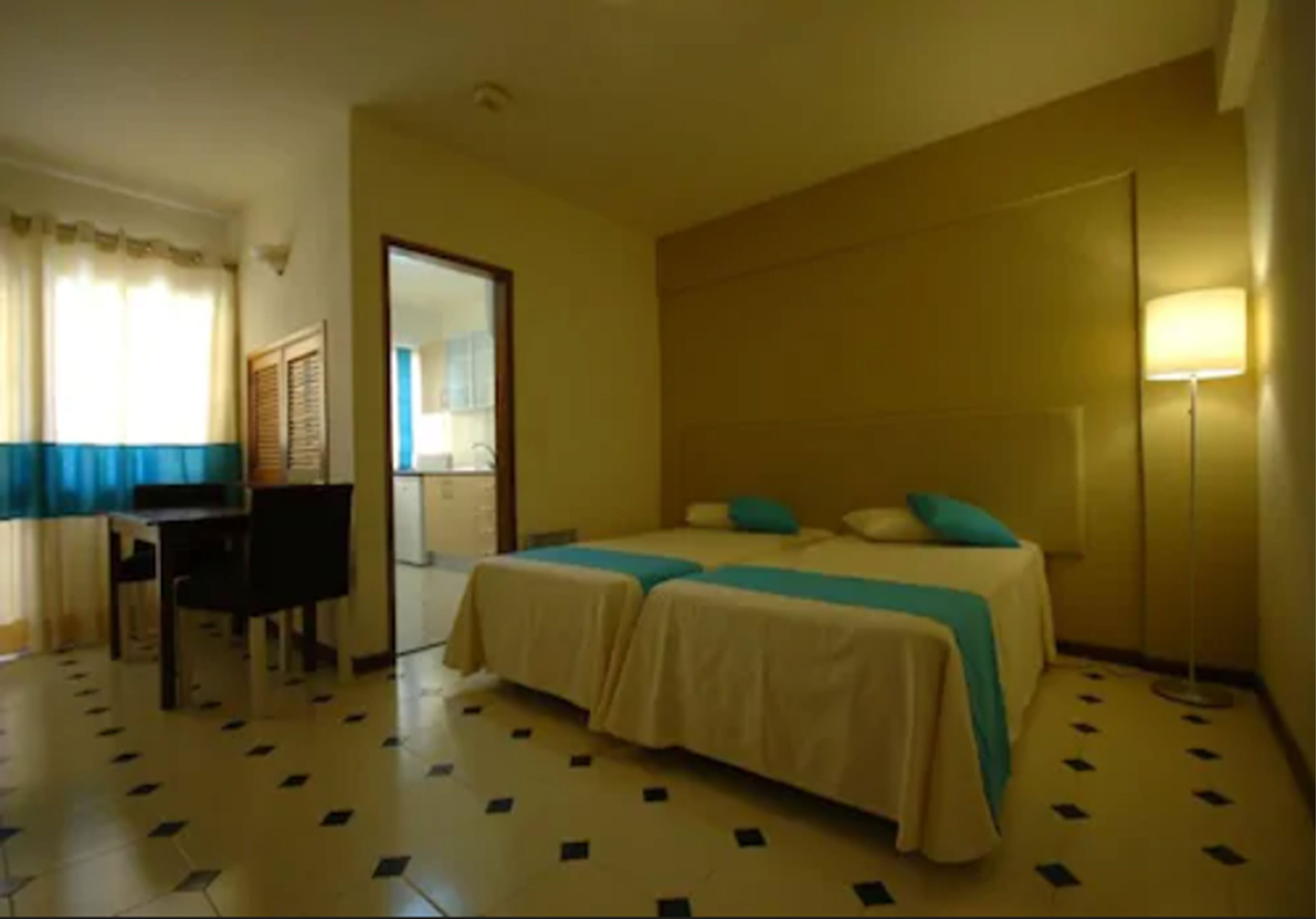 A hotel room with two beds, a desk, and a chair.