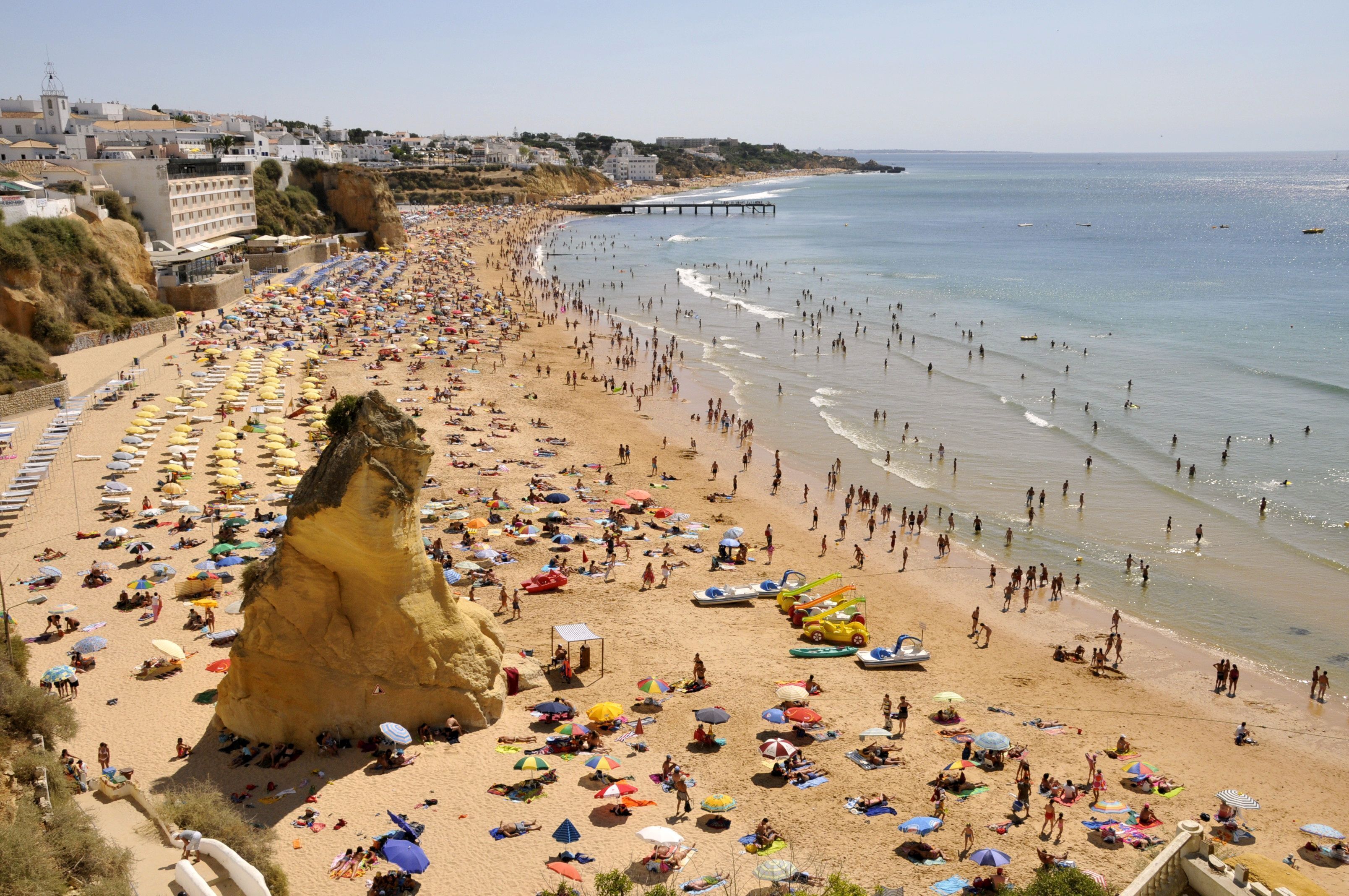 A crowded beach with numerous umbrellas and people.