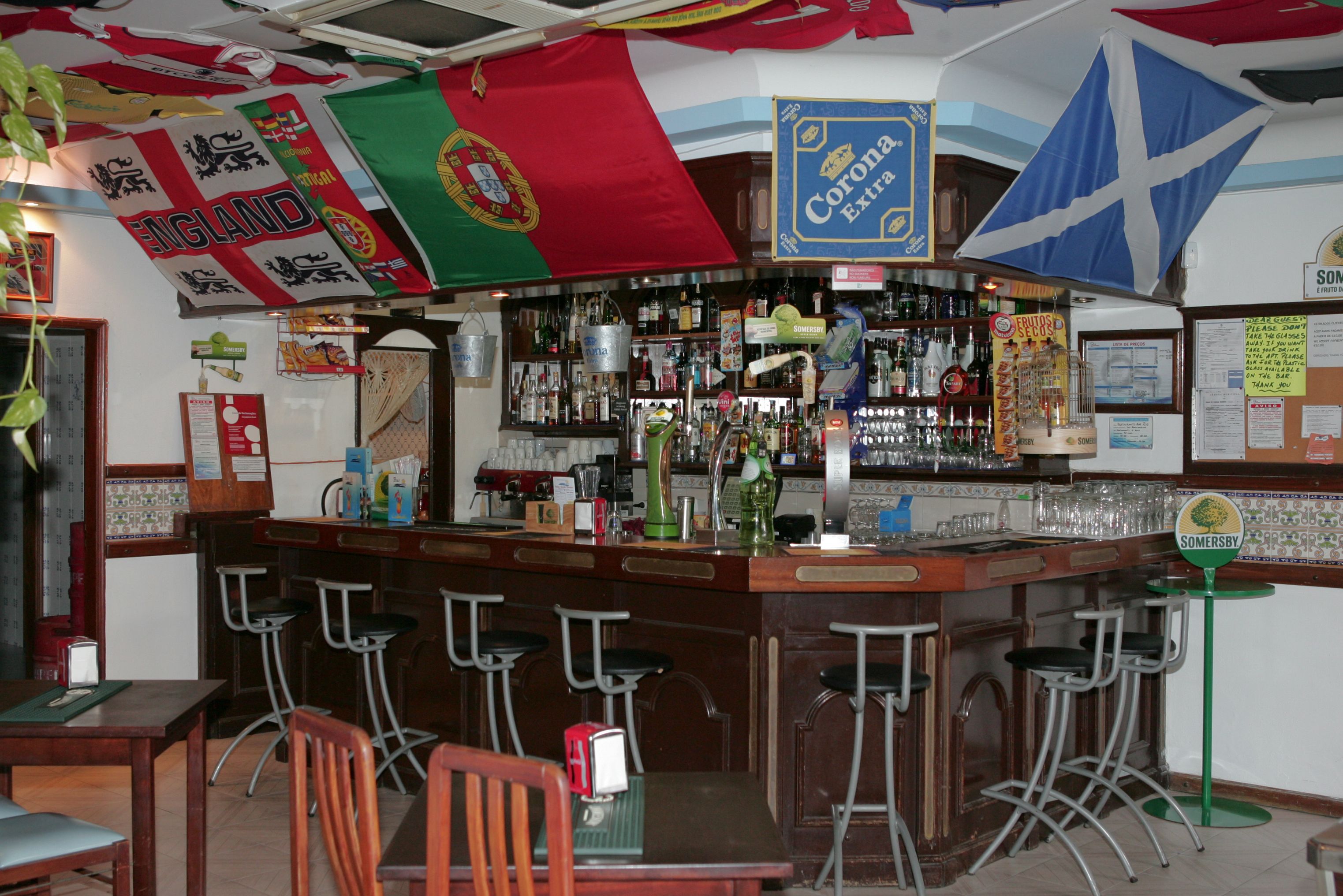 A bar area with stools, a bar counter, and various flags.