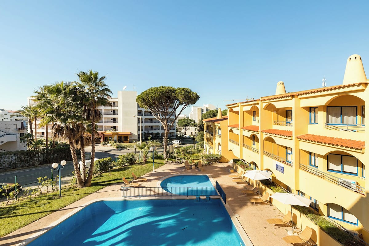 Um hotel com piscina, área de estar ao ar livre e vista dos edifícios ao redor.