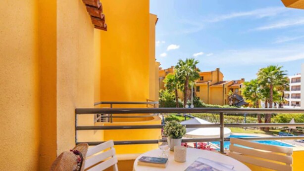 A balcony with a white table, chairs, and a hat hanging on the wall. - Rio Apartments (Loulé)