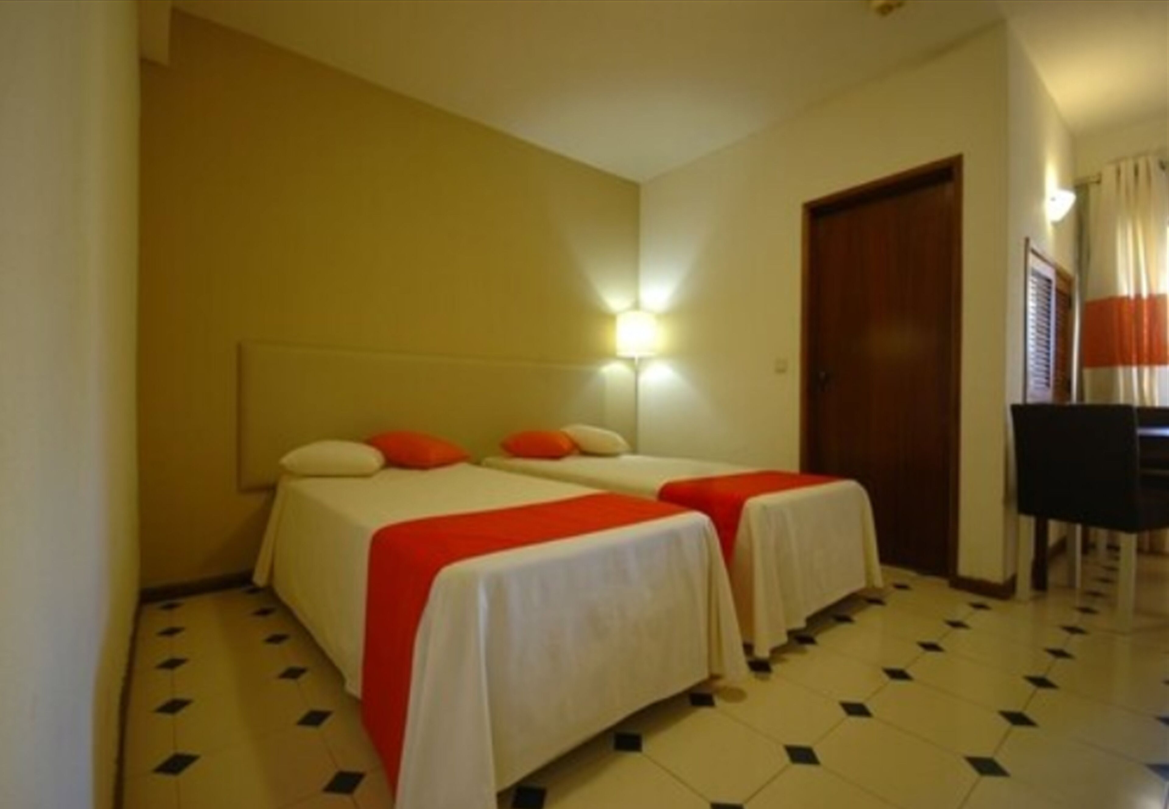 A hotel room with two beds, a desk, and a chair.