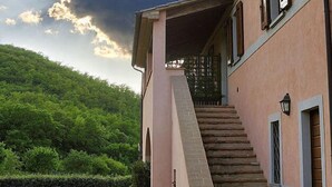 Une maison à deux étages avec un escalier en pierre menant à un porche abrité.