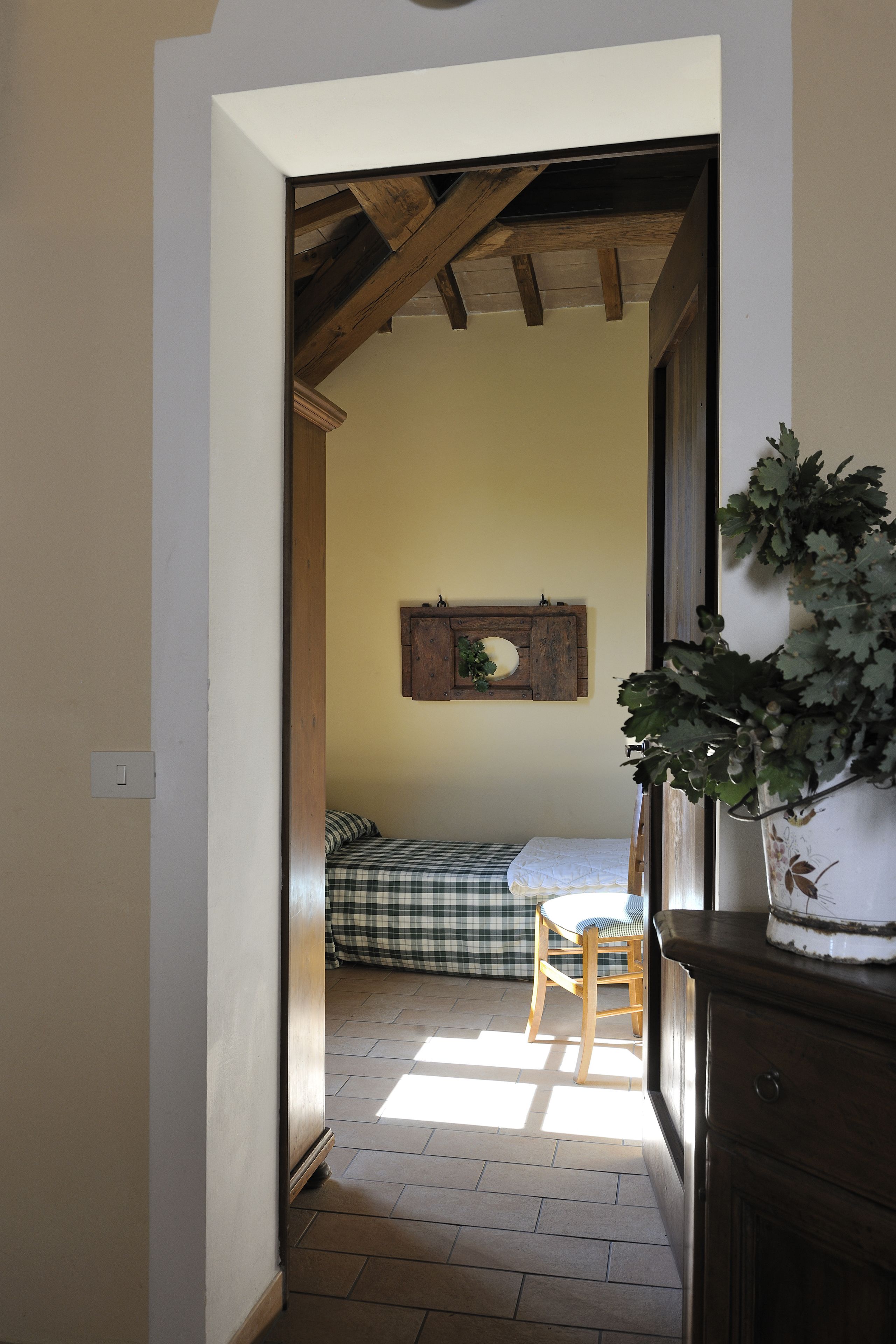 Un couloir étroit mène à une chambre qui contient un lit, une chaise et une armoire en bois.