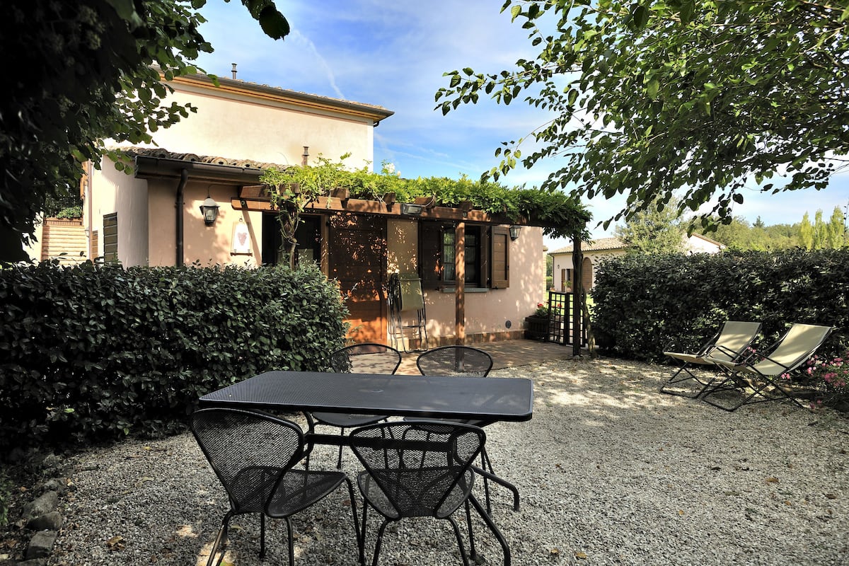 A patio with a table and chairs, surrounded by a gravel path and greenery.