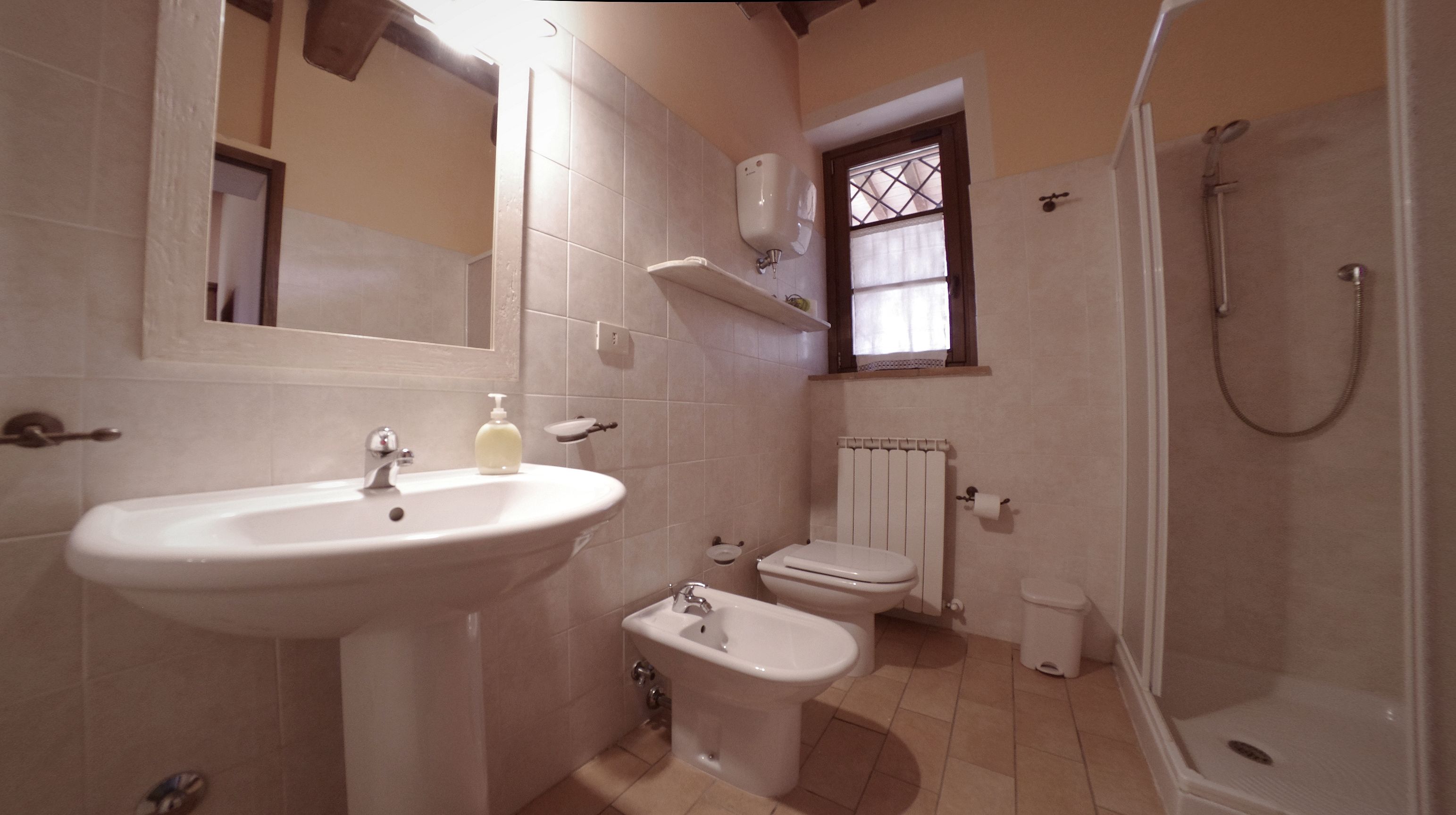 A bathroom with a sink, bidet, toilet, and shower.