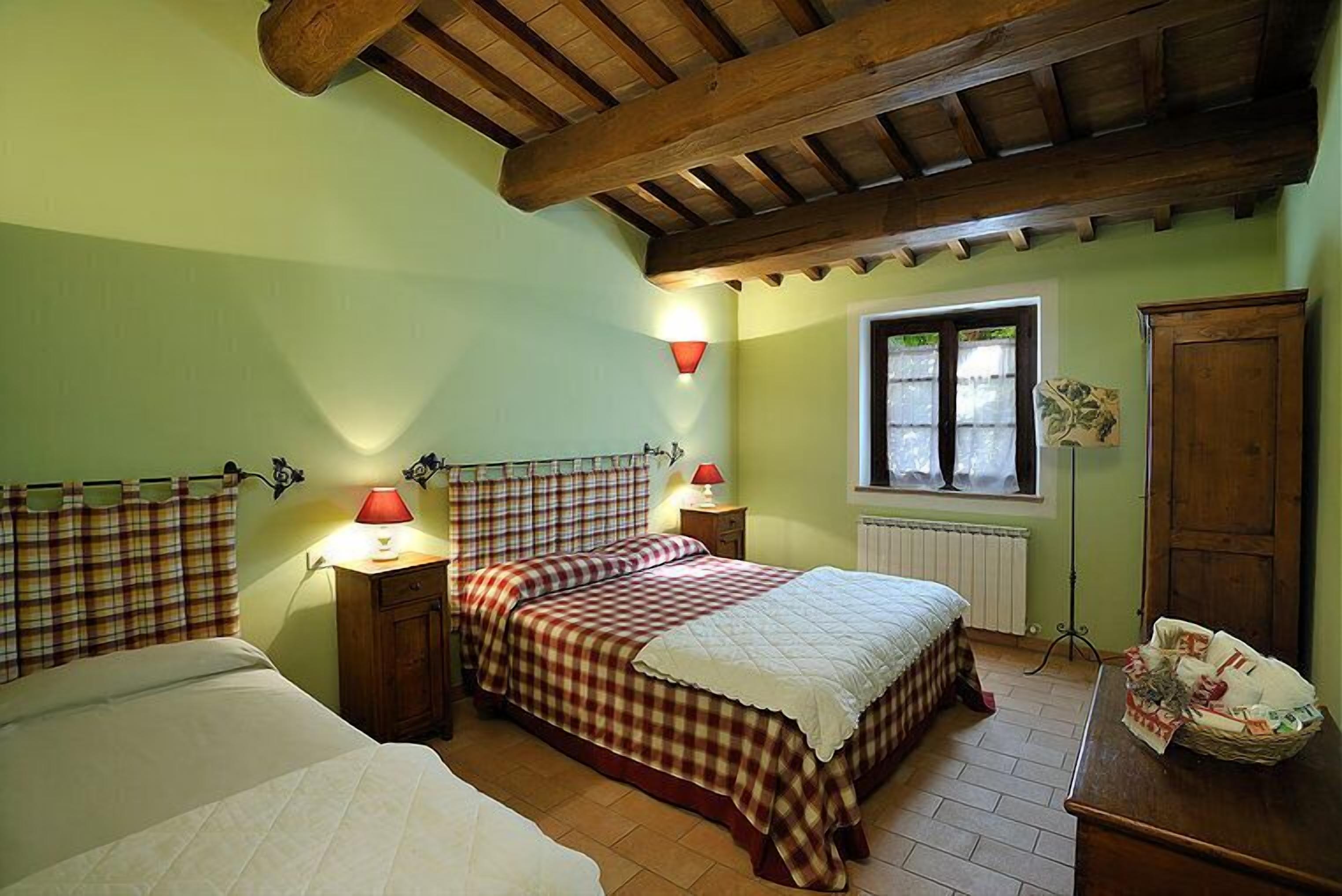 Une chambre avec deux lits, une fenêtre avec des rideaux, un radiateur et un plafond en bois.