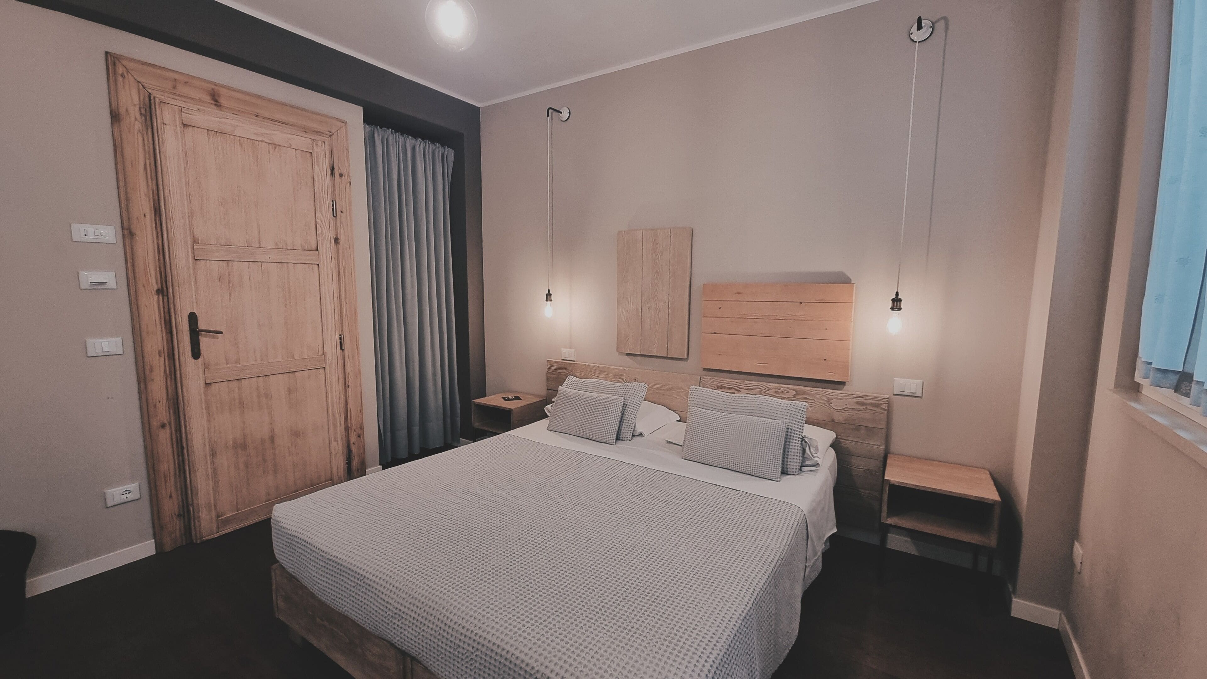 A bedroom with a large bed, wooden wardrobe, bedside tables, and a nightstand.