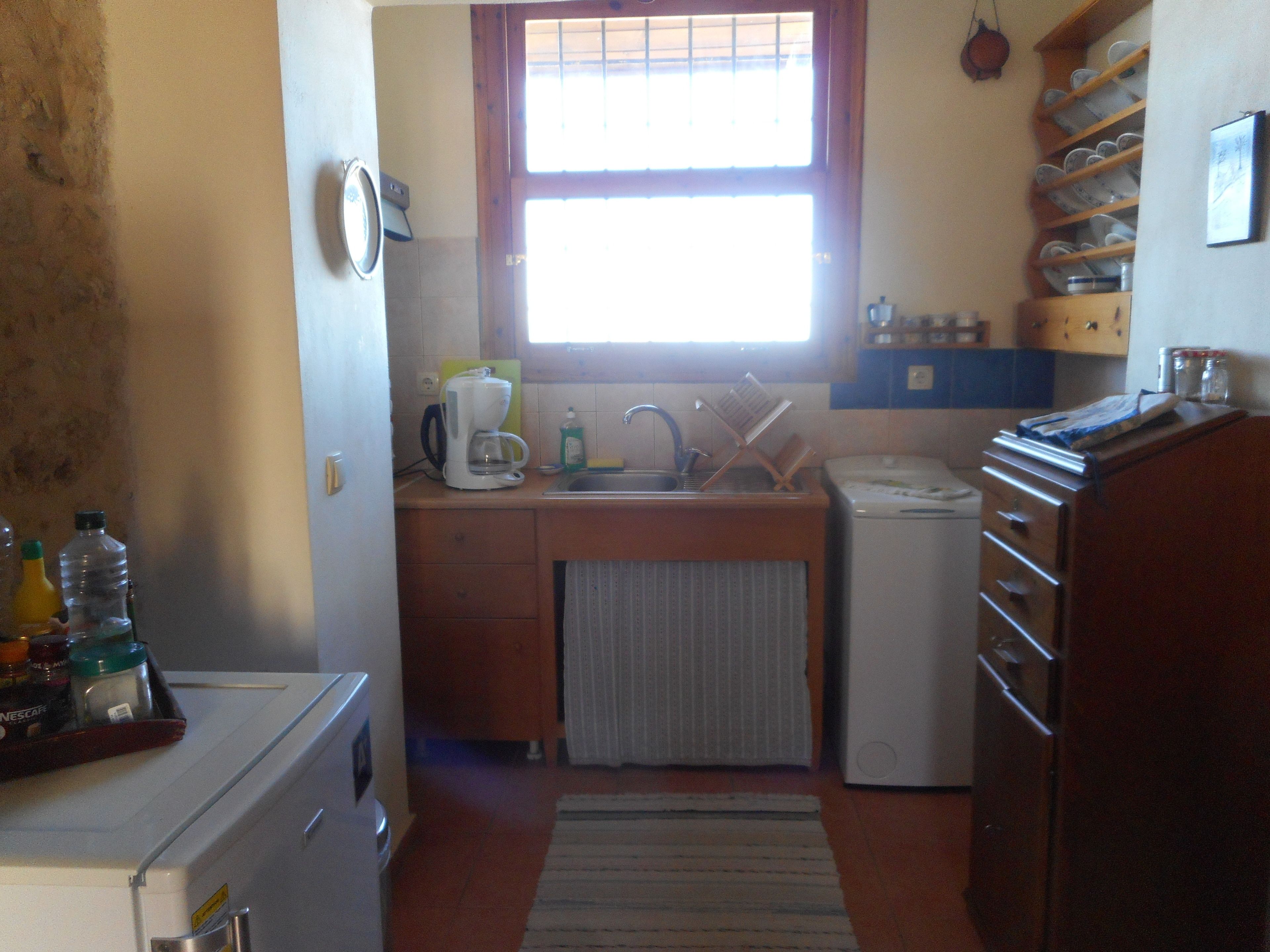 A compact kitchen with a sink, a coffee maker, and a refrigerator.