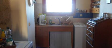 A compact kitchen with a sink, a coffee maker, and a refrigerator.
