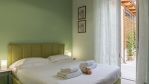A neatly made bed with white linens and towels, a bedside lamp, and two framed pictures on the wall. - Pilastri Garden by Mmega (Florence)