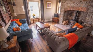 A cozy living room with a fireplace, two sofas, a coffee table, and a wooden floor.