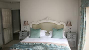 A bedroom with a bed, two bedside tables, a nightstand, a door, and a curtain.