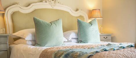 A neatly made bed with a quilted cover, two pillows, and a decorative headboard.