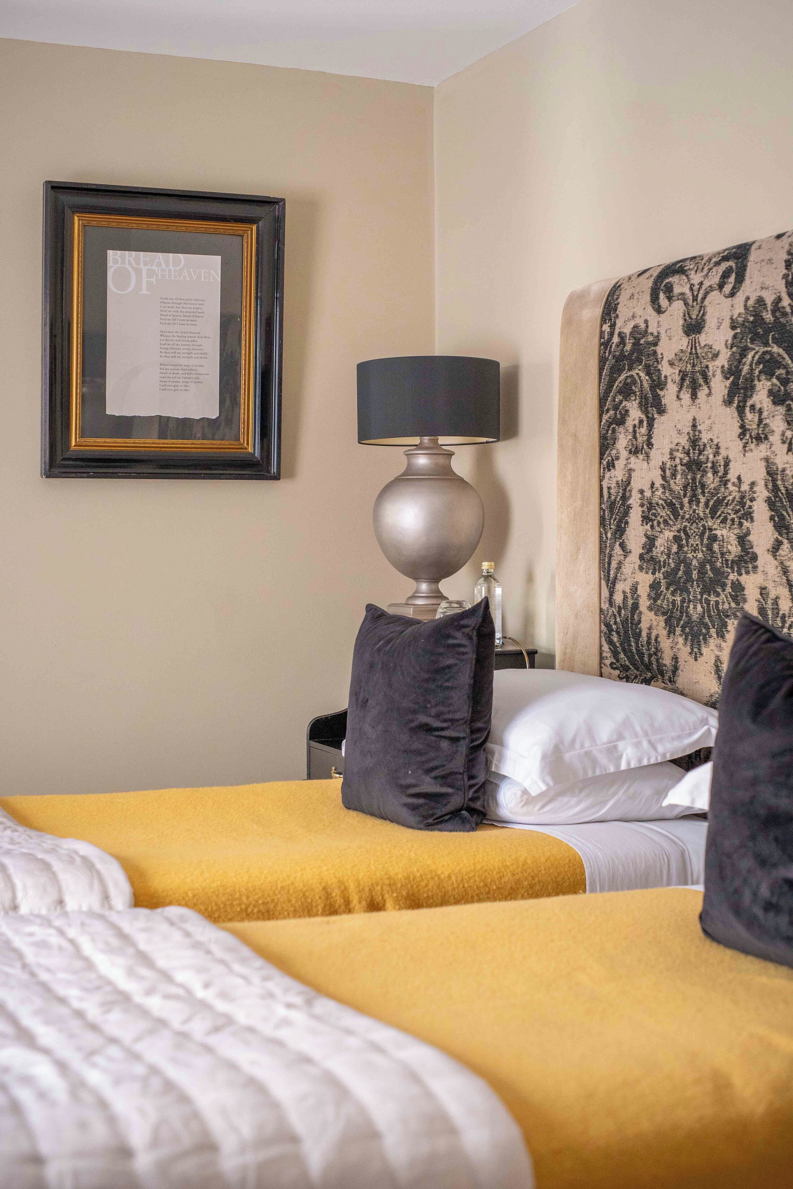 A hotel room with two beds, a framed menu on the wall, a lamp, and a patterned headboard.