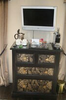 Un minibar con un televisor, una cafetera y un refrigerador para vino.