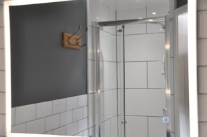A modern bathroom with a glass shower enclosure, white tiled walls, and a dark accent wall. - Haisthorpe House (Windermere)