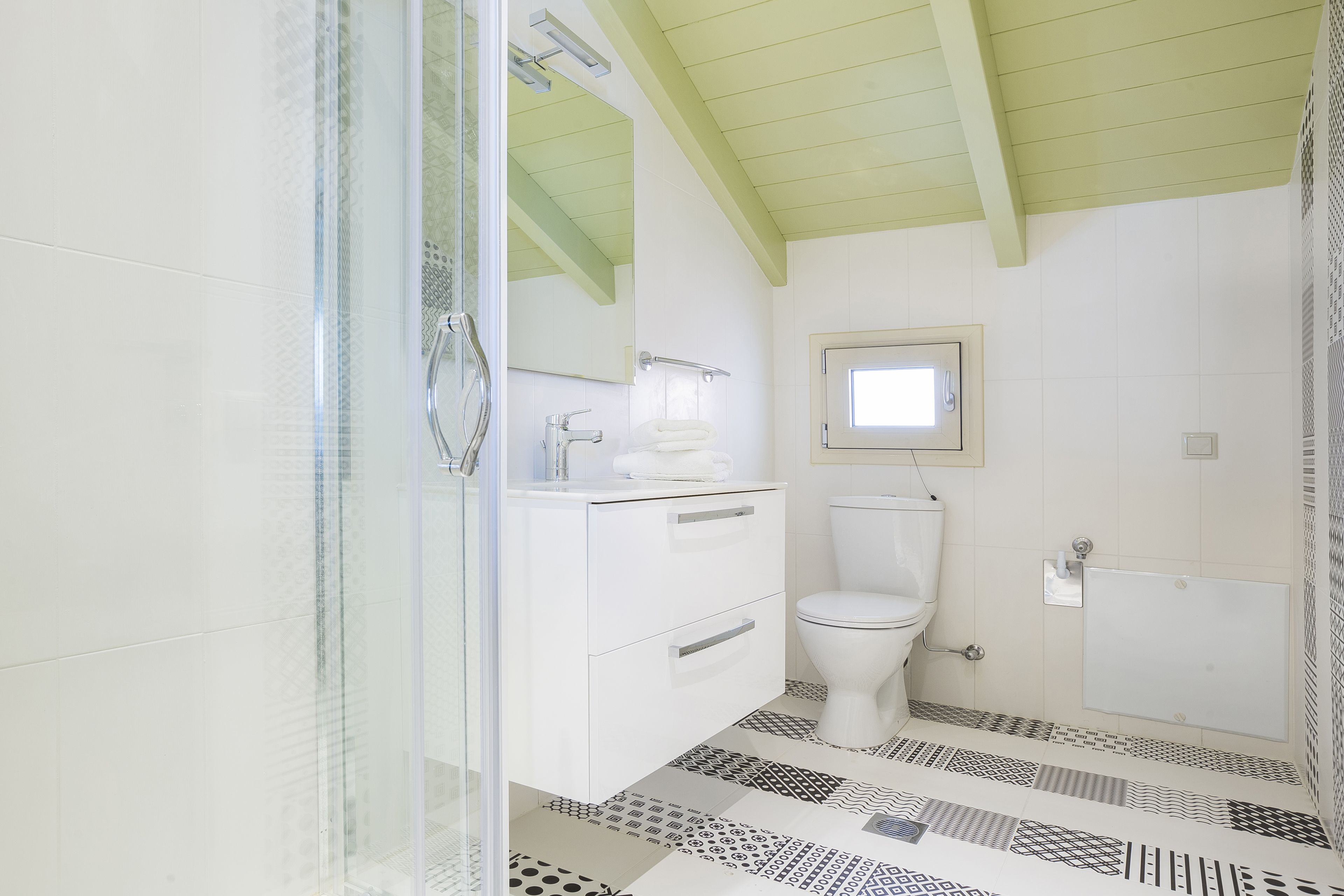 A bathroom with a glass shower enclosure, a white sink with a mirror, a toilet, and a bathtub.
