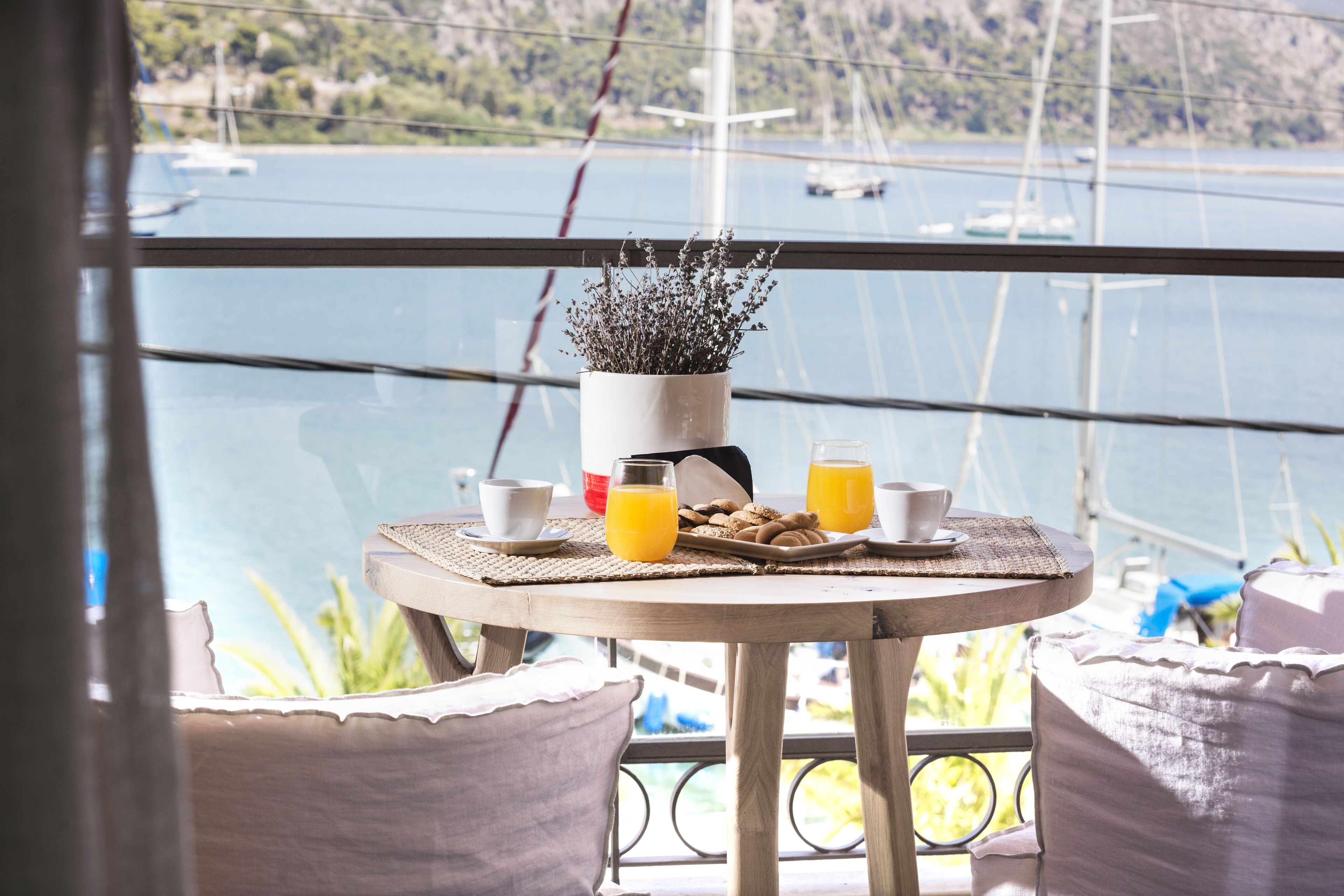 A balcony with a table set for breakfast, overlooking a body of water with boats.