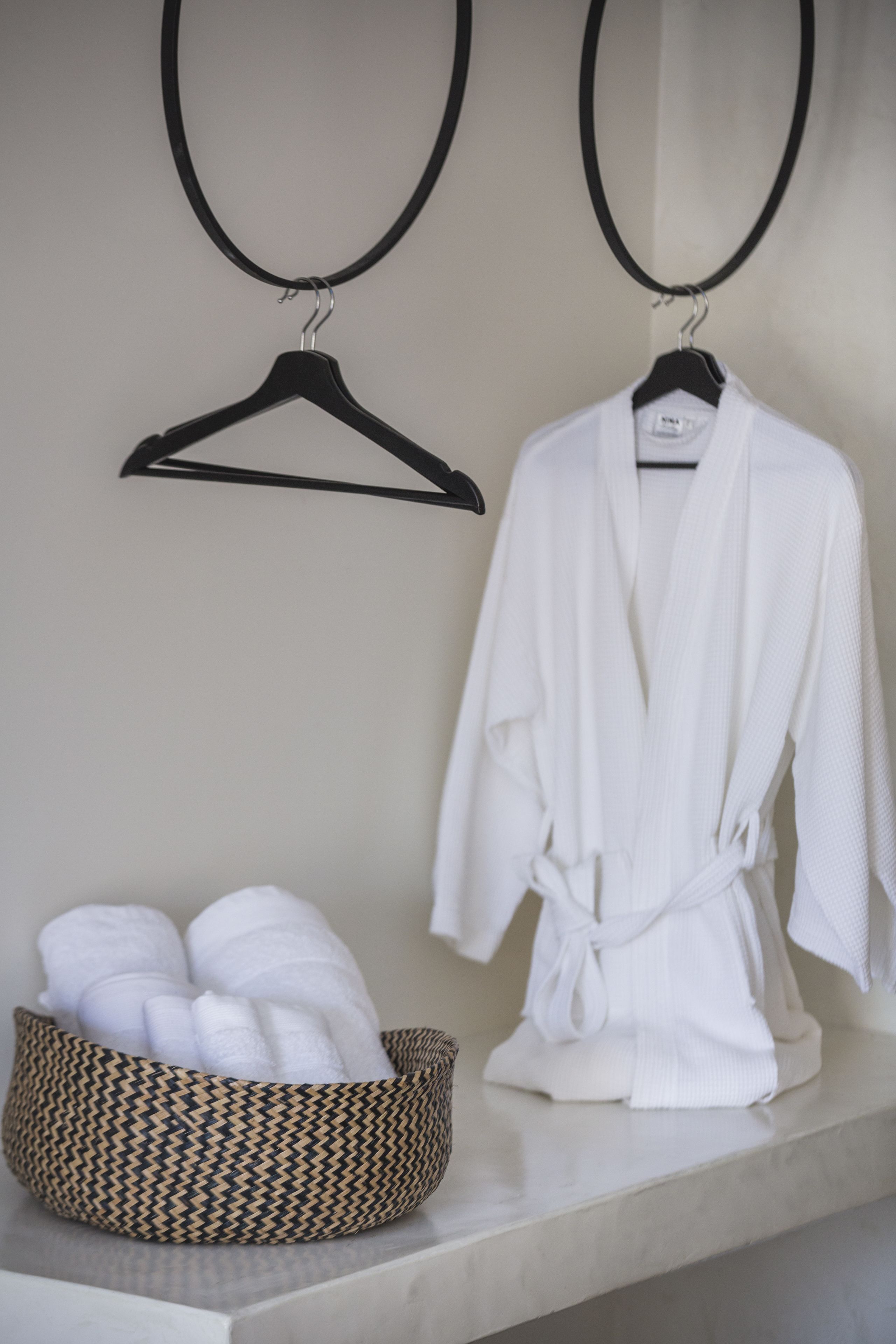 Une salle de bain équipée d’un porte-serviettes, d’un peignoir blanc et d’un panier en osier contenant des serviettes.