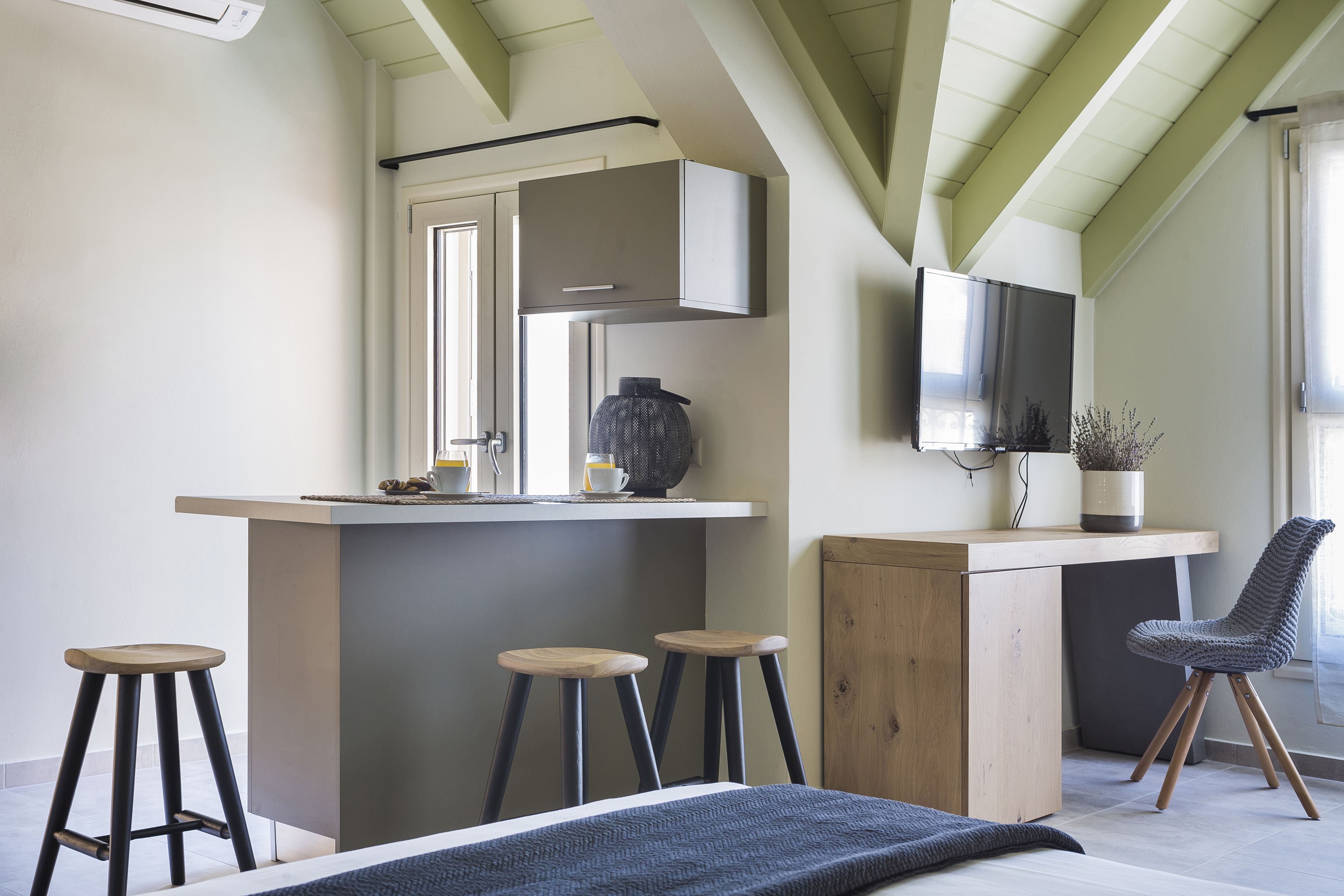 Una cocina moderna con una isla integrada, taburetes de bar, un mueble de madera y un televisor montado en la pared.