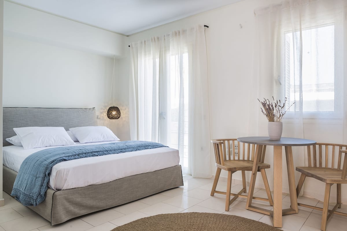 A bedroom with a bed, a bedside table, a chair, and a window with curtains.