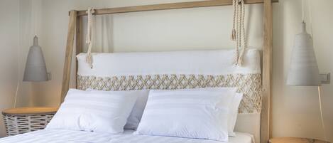 A neatly made bed with white linens and a wooden headboard with rope details. There are two bedside tables with lamps and a woven basket.