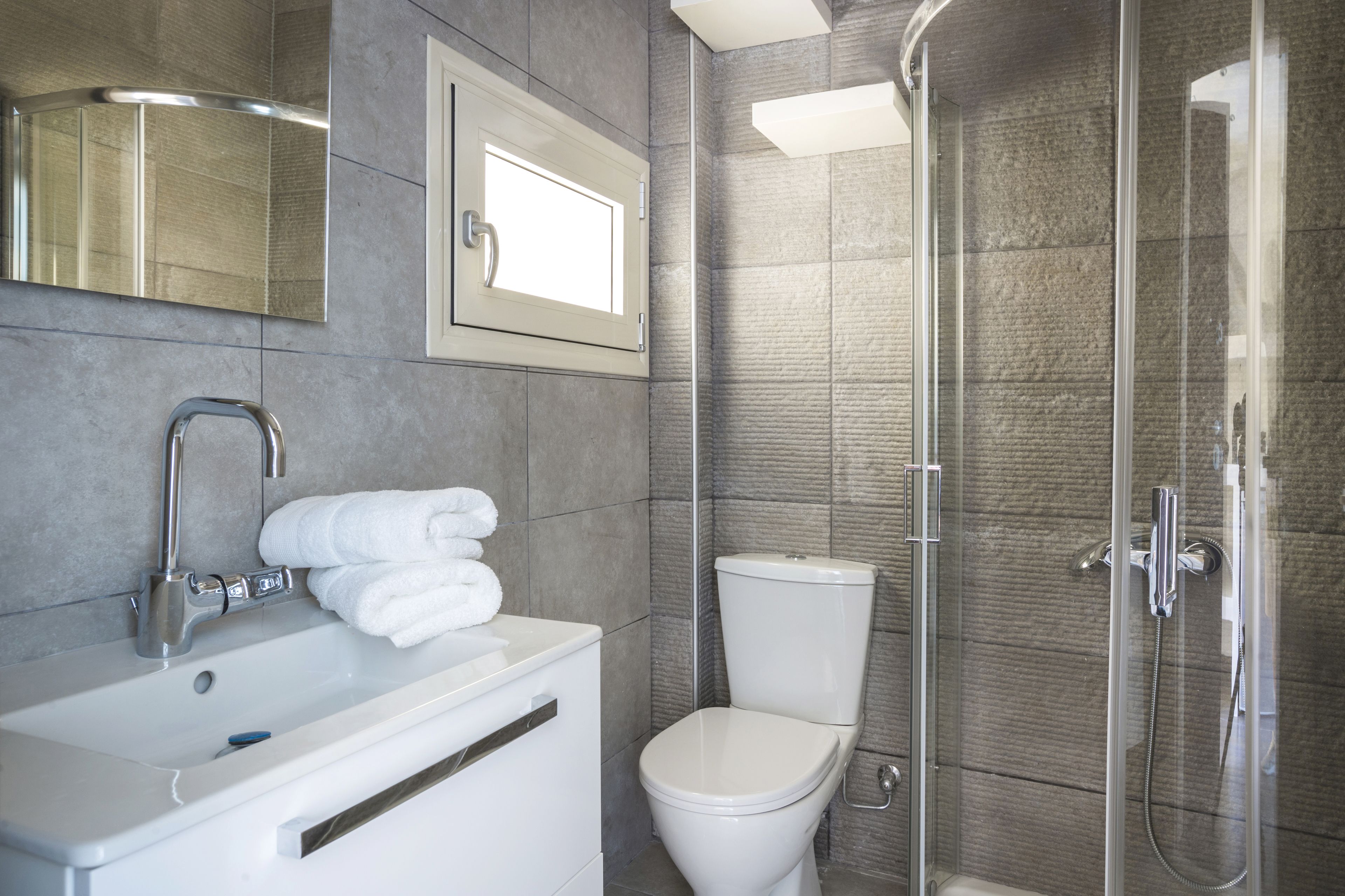 A modern bathroom with a white sink, a toilet, and a glass-enclosed shower.