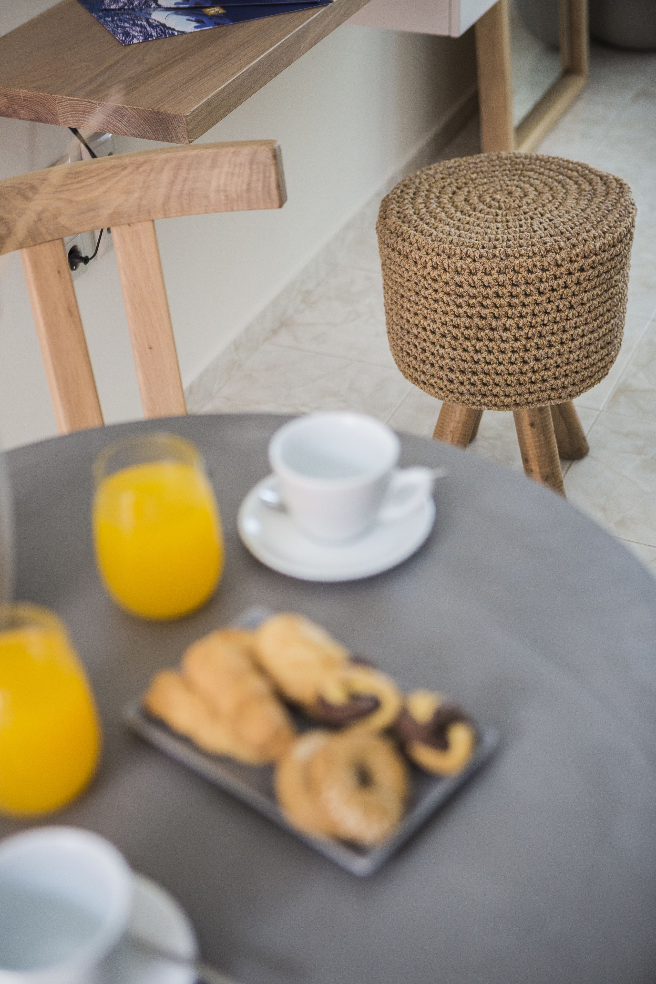 A breakfast table with orange juice, a cup, and pastries.