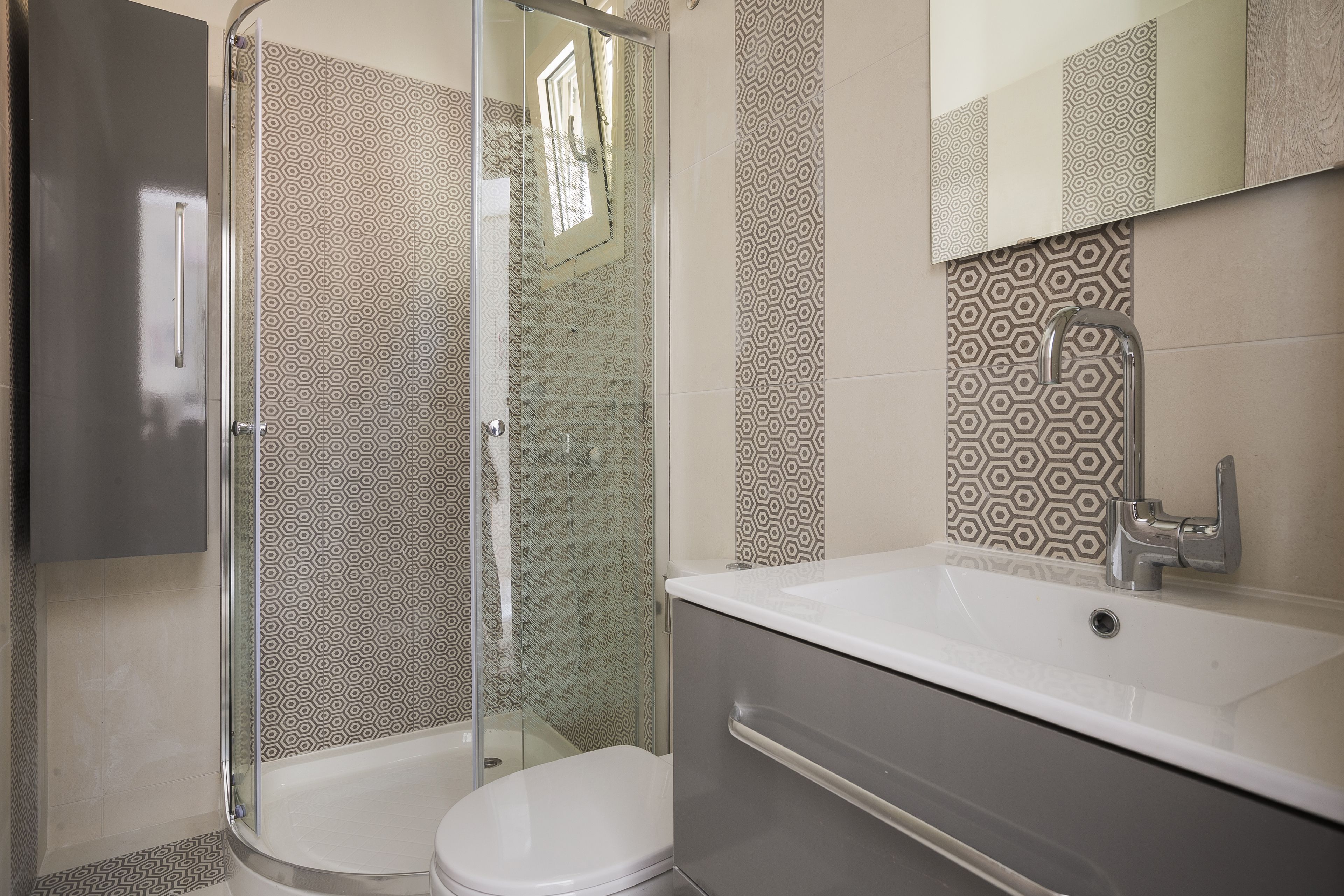 Un baño con cabina de ducha de vidrio, inodoro blanco y tocador con espejo.