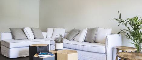 A modern living room with a white sofa, two wooden side tables, and a potted plant.