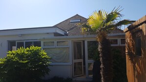 A house with a conservatory, a tiled roof, and a wooden fence. - John Wayne Lodge (Peacehaven)