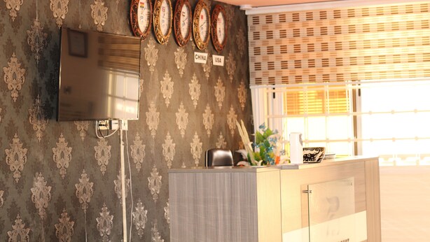 A reception area with a TV, a wall-mounted clock, and a sign indicating 'China' and 'USA'. - Platinum Court (Oyarifa)