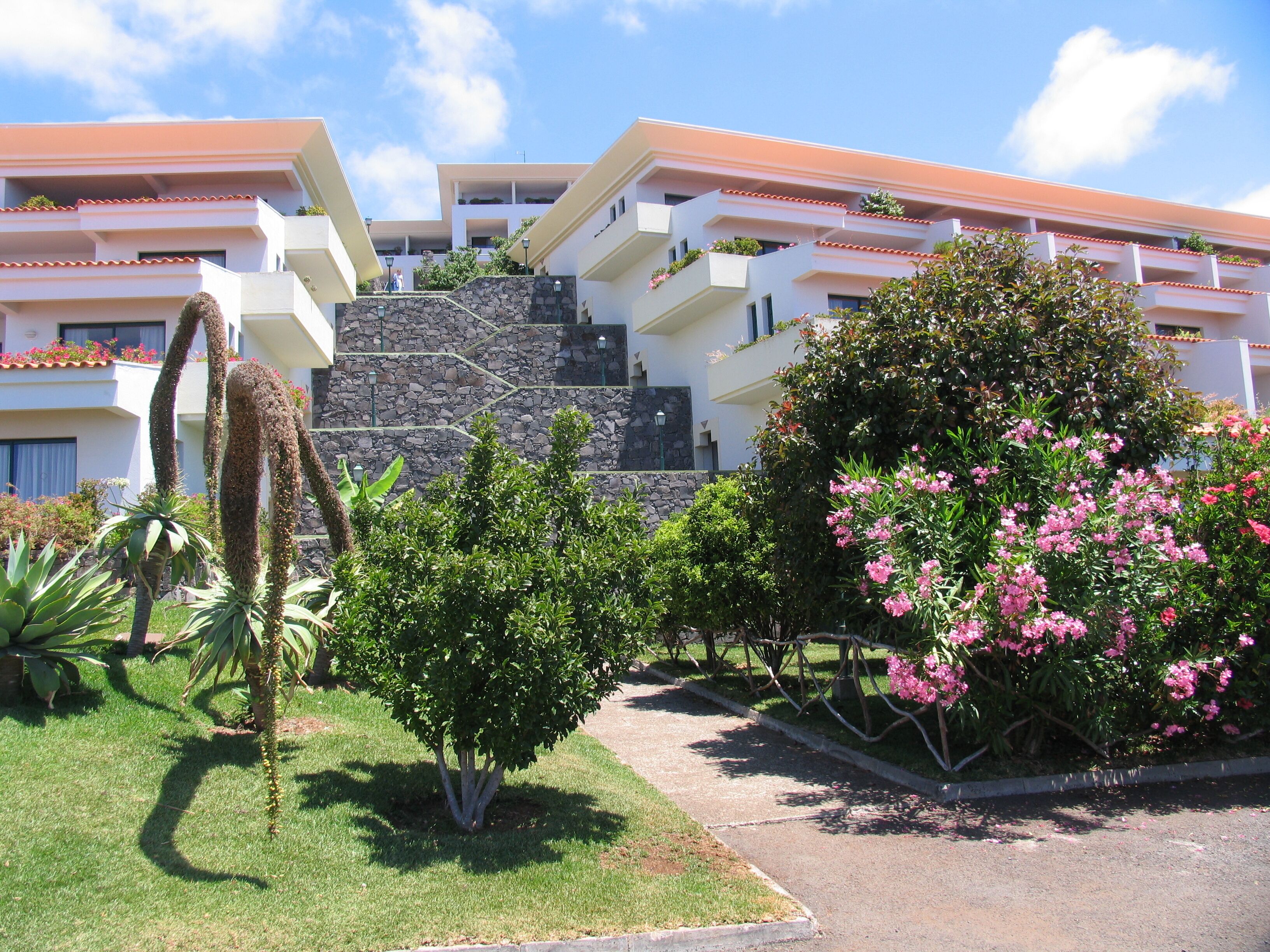 Um hotel com fachada de pedra, várias varandas e vegetação exuberante.