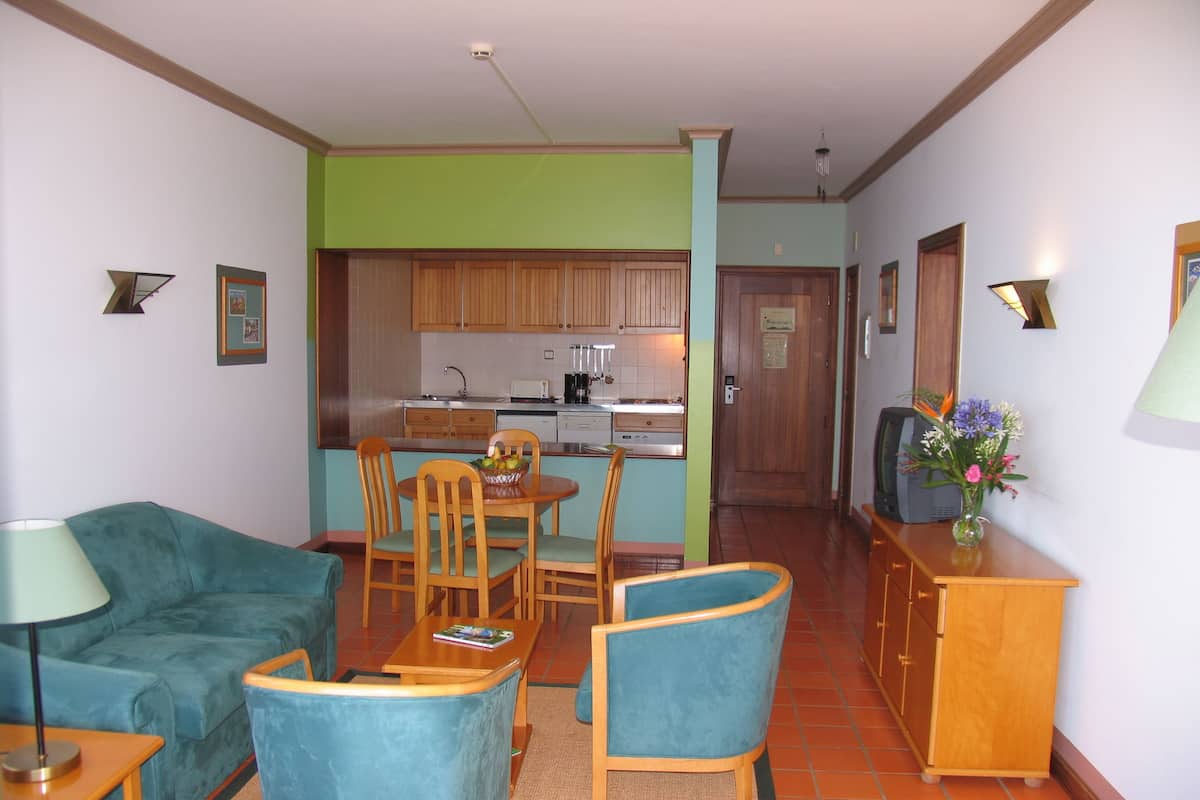 A compact living space with a dining area, kitchenette, and a television.