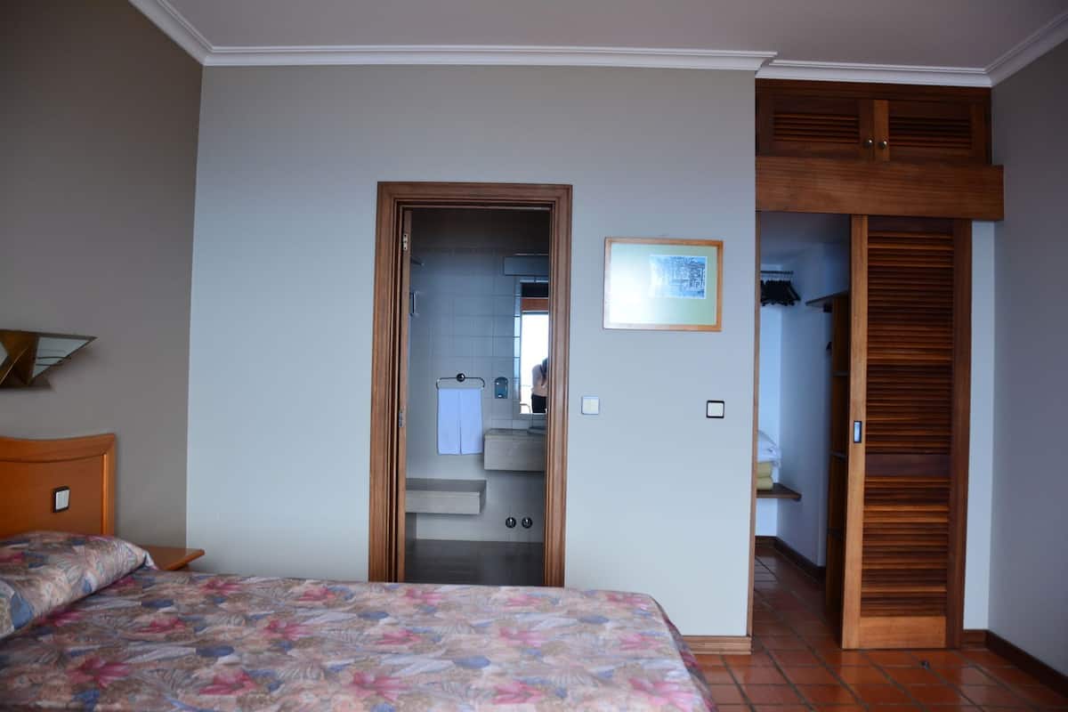 A bedroom with a bed, a bathroom visible through an open door, and a wooden closet.